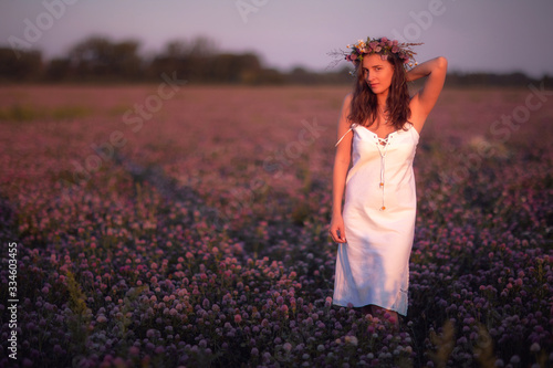 young girl in a white dress stands in a field