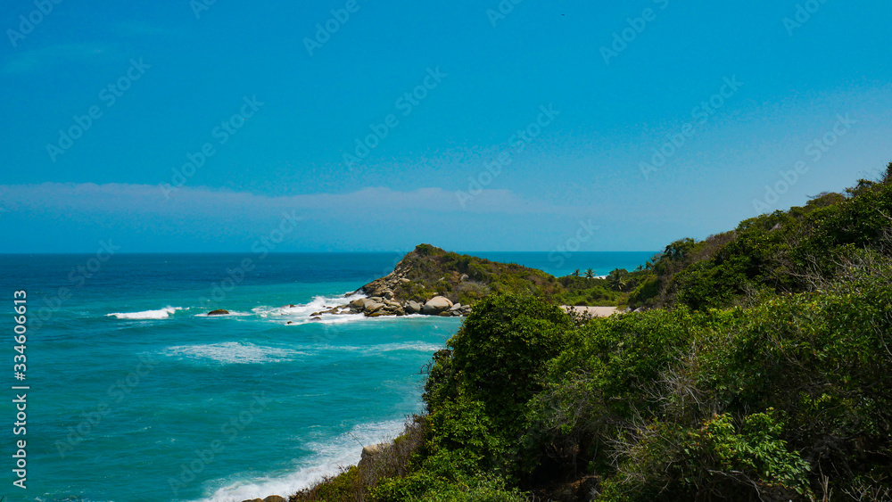 Coast view of the National Park Tayrona in Colombia. Caribbean Sea paradise, natural scenery with a bright blue sky and beautiful beach.