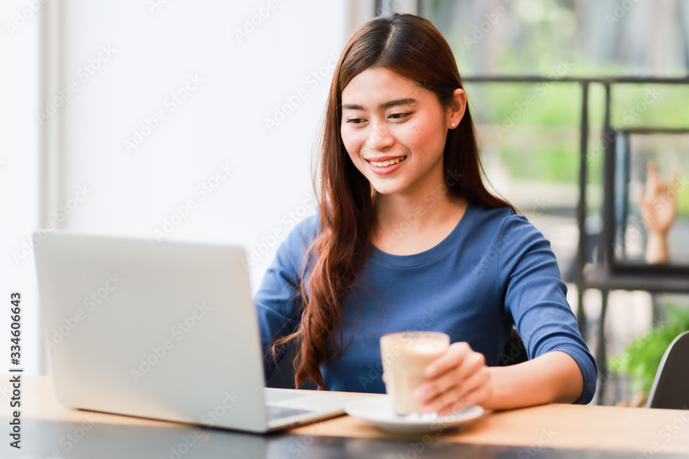Asian woman using computer laptop and drink coffee work from home concept Asian woman using computer laptop and drink coffee work from home concept