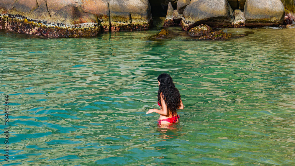Young woman swimming in the beach with turquoise waters. Positive human emotion. Free happy girl enjoying nature. Tayrona National Park, Cabo San Juan, Colombia.