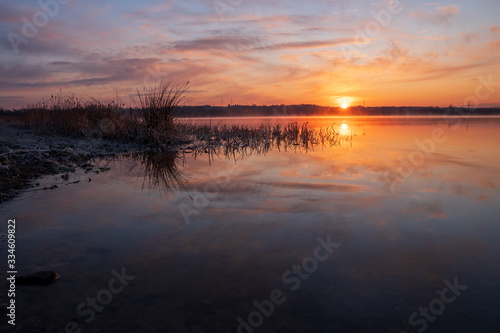 Gorgeous sunrise over the lake with reflection of the sun on the lake and spring