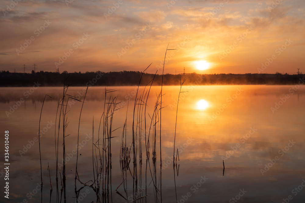 Gorgeous sunrise over the lake with reflection of the sun on the lake and spring