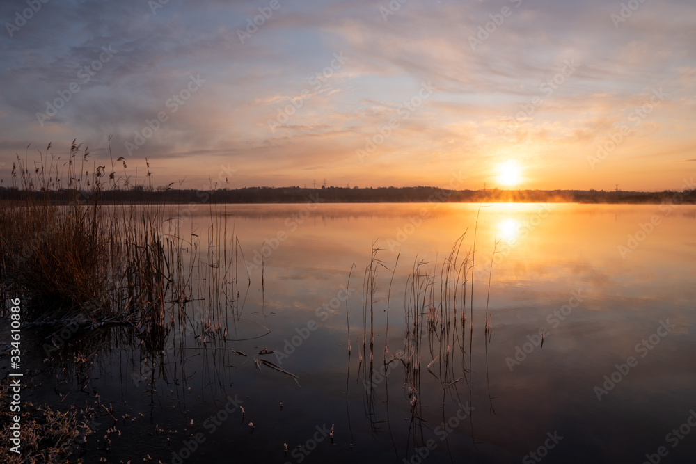 Gorgeous sunrise over the lake with reflection of the sun on the lake and spring