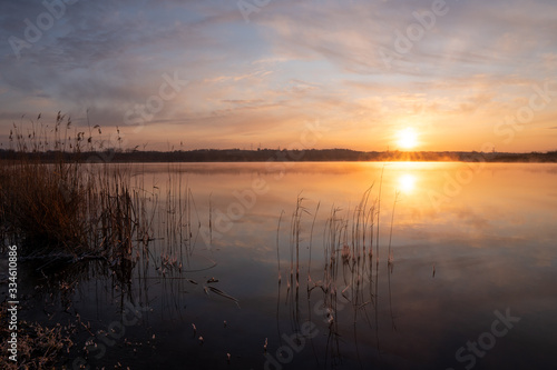 Gorgeous sunrise over the lake with reflection of the sun on the lake and spring © Martin