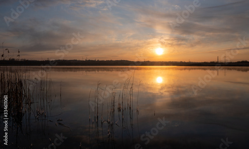 Fototapeta Naklejka Na Ścianę i Meble -  Gorgeous sunrise over the lake with reflection of the sun on the lake and spring