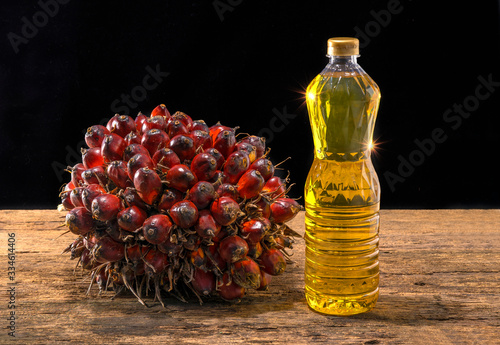 Fresh oil palm fruits and cooking palm oil on wooden background photo