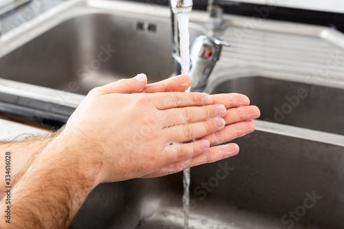 Man washing hands with antibacterial soap and water in metal sink for corona virus prevention. Hand hygiene, health care, medical concept. Hand skin disinfection protect from Coronavirus covid 19