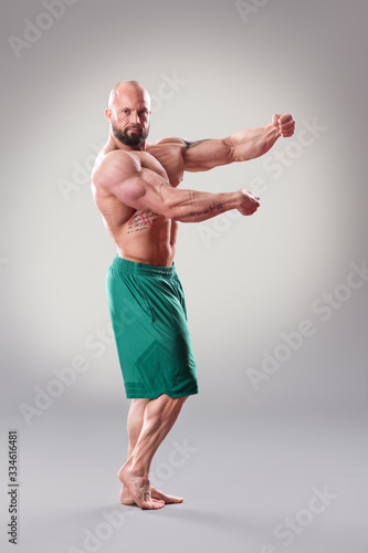 Sexy Muscular bodybuider posing on the gray background photo