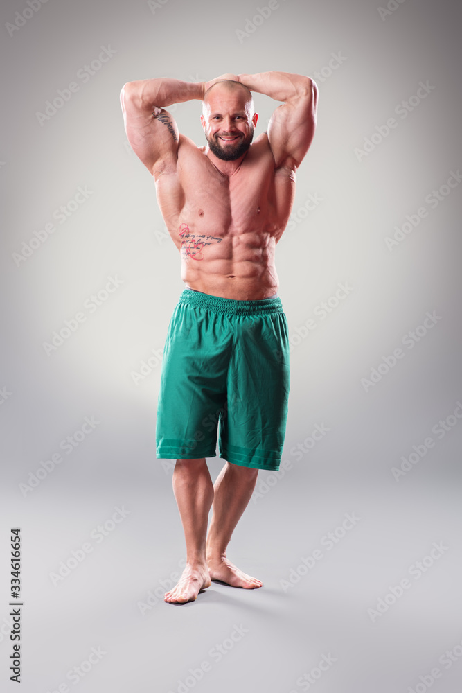 Sexy Muscular bodybuider posing on the gray background