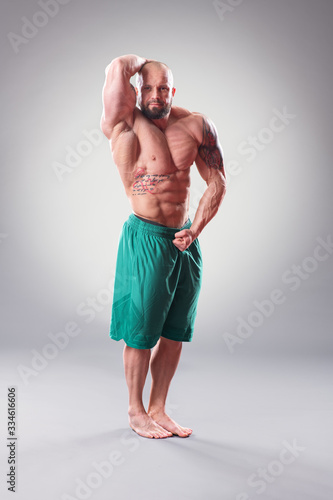 Sexy Muscular bodybuider posing on the gray background photo