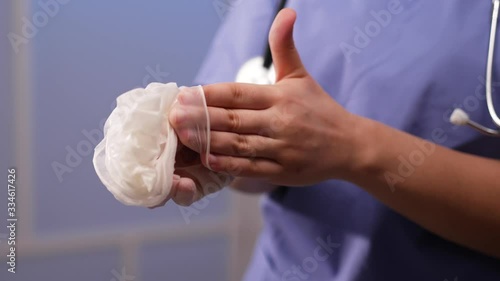 A medical professional showing the proper sterile technique of removing and disposing of medical gloves (PPE), to avoid spread of infection and contamination of other people and objects.