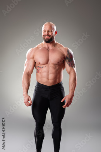 Sexy Muscular bodybuider posing on the gray background photo