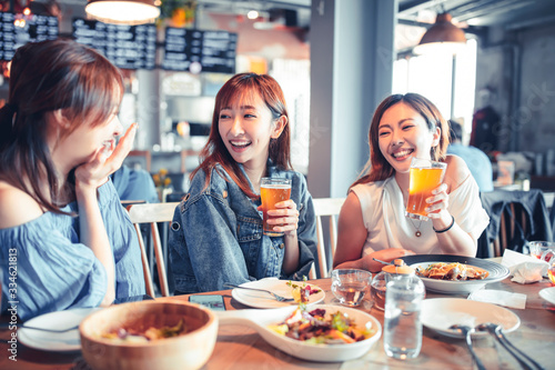 happy young woman sitting in  restaurant and enjoy dinner and beer © Tom Wang