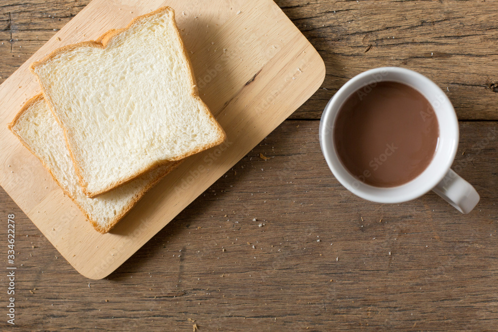 Top view of Breakfast bread and coffee in a white cup on a wooden table with morning sunlight and copy space Top view of Breakfast bread and coffee in a white cup on a wooden table with morning sunlight and copy space