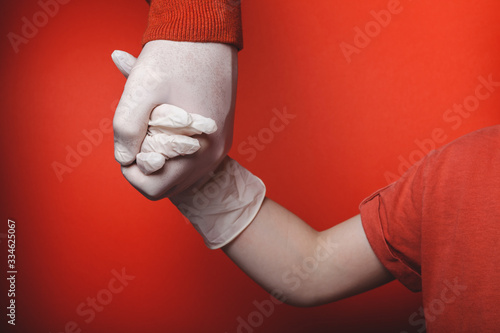 Dad and son are holding hands in disposable medical gloves. Quarantine Concept photo