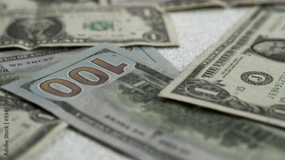 American dollars lie on a bright shiny background. The camera slowly moves forward and focuses on banknotes of various denominations. slow motion money view American dollars lie on a bright shiny background. The camera slowly moves forward and focuses on banknotes of various denominations. slow motion money view