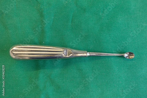 on green surgical drape lies a sharp spoon for an operation