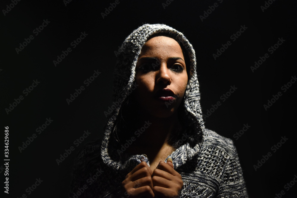 young African woman posing at studio, face with hand portrait over dark background	