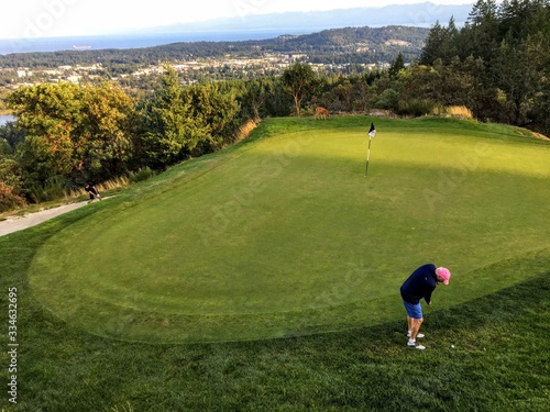  A father and son on a putting green playing golf surrounded by beautiful scenery outside of Victoria, British Columbia, Canada.