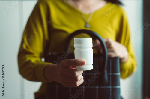 Hands woman holding a medicine pills bottle into handbag,Healthy and lifestyle concept