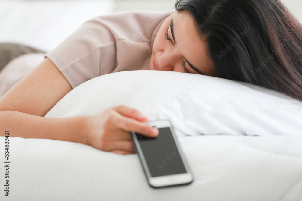 Woman sleeping on bed while holding phone. Woman sleeping on bed while holding phone.