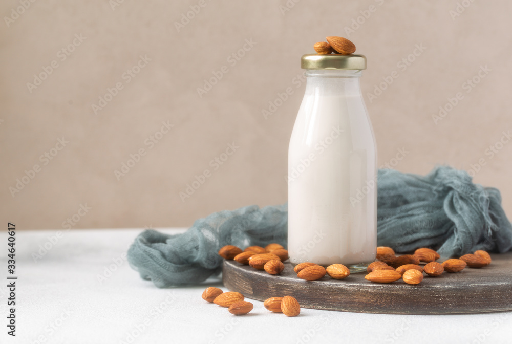 Almond milk in glass bottle with almond nuts on wooden cutting board. Almond milk in glass bottle with almond nuts on wooden cutting board.