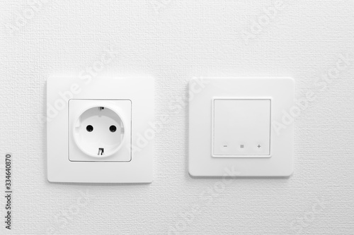 Electric outlet and switch for comfortable under floor heating system on white empty wall, front view, close up. Renovation of the apartment, wiring and sources of electricity.
