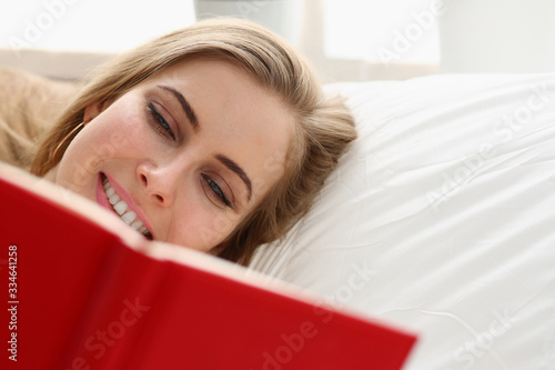 young blond pretty woman read book stay in bed