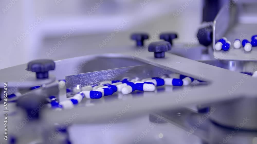 Close up shot from blue and white pills in a machine. Covid-19 pandemic cure. Coronavirus Close up shot from blue and white pills in a machine. Covid-19 pandemic cure. Coronavirus