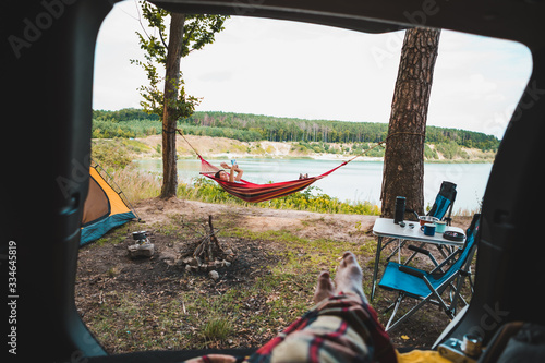 Fototapeta Naklejka Na Ścianę i Meble -  person view couple resting at camping woman laying in hammock with beautiful view of forest lake
