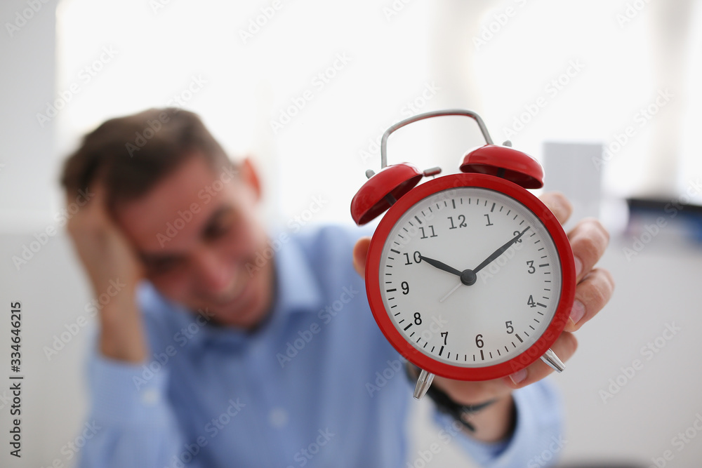 Smiling business woman holding in hand on the alarm clock a red color showing ten o'clock in the morning or evening AM PM Smiling business woman holding in hand on the alarm clock a red color showing ten o'clock in the morning or evening AM PM