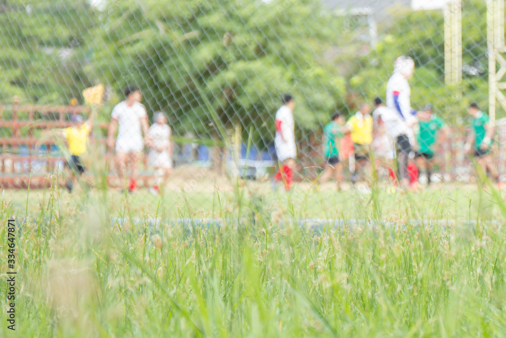 Obraz premium Abstract blurry shot of people relaxing by playing football or soccer at the stadium.