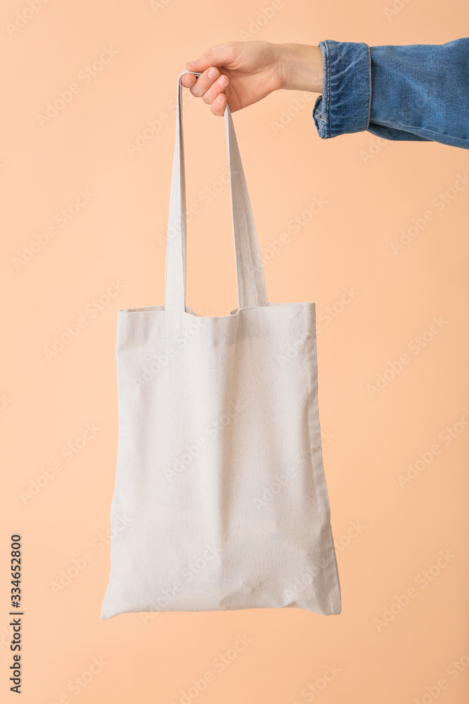 Female hand with eco bag on color background Female hand with eco bag on color background