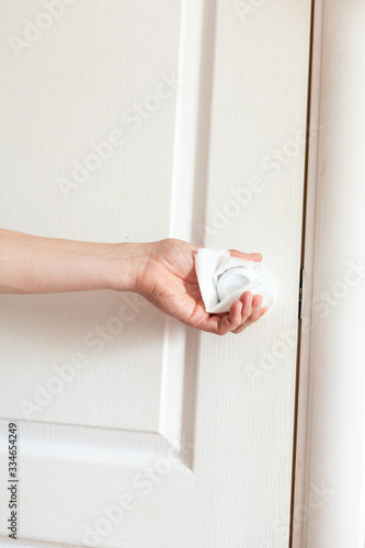 Coronavirus COVID-19 Prevention wiping doorknob with antibacterial disinfecting wipe for killing corona virus on touching surfaces or touching public bathroom handle with tissue. photo