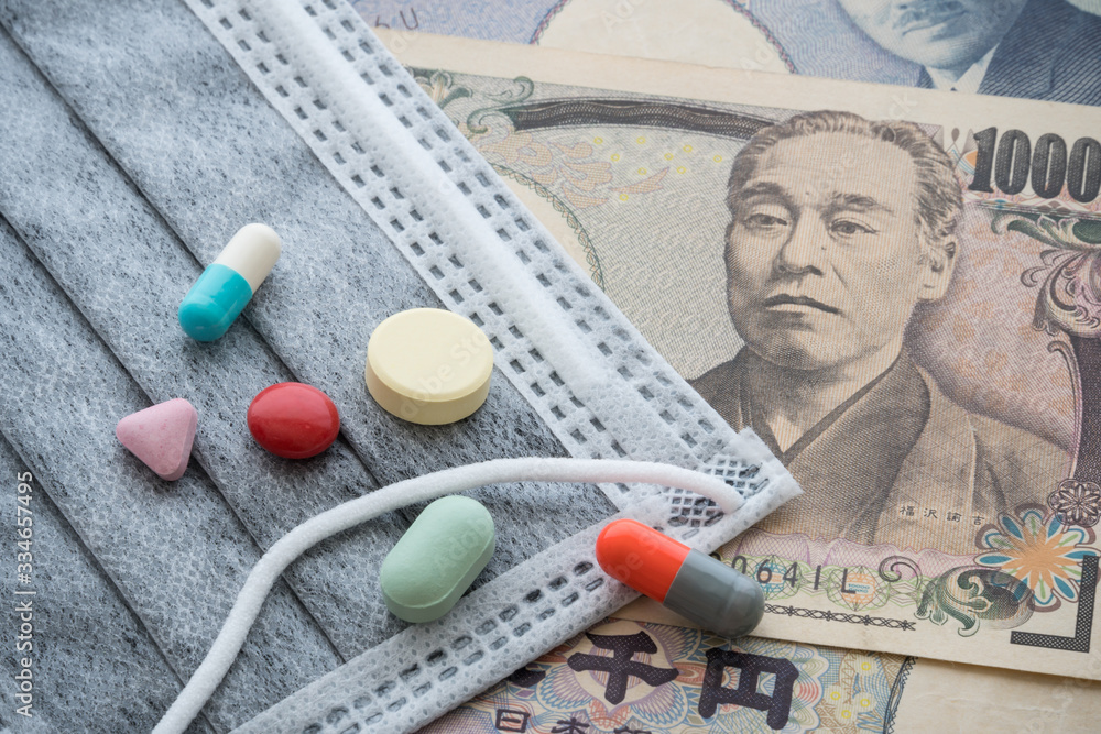 Gray face mask and medicine pill, tablets on Japanese yen bill banknote background. Global novel coronavirus (Covid-19) outbreak effect to world economy and financial crisis, travel hotel business. Gray face mask and medicine pill, tablets on Japanese yen bill banknote background. Global novel coronavirus (Covid-19) outbreak effect to world economy and financial crisis, travel hotel business.