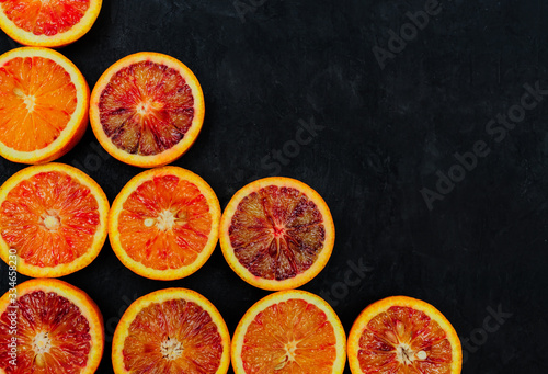 Organic Raw Red Blood Oranges in a rows on a black background. Copy space for text.