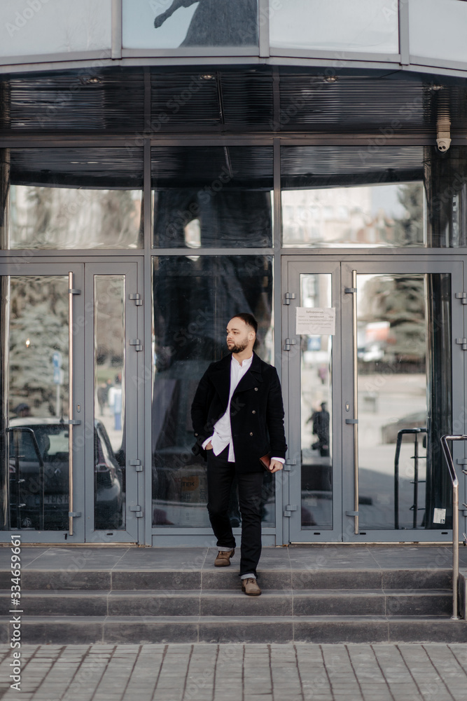 Portrait of fashionable well dressed man with beard posing outdoors