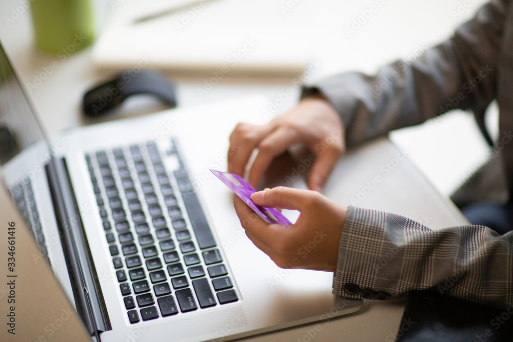 Obraz premium Young businesswoman holding a credit card and typing. On-line shopping on the internet using a laptop