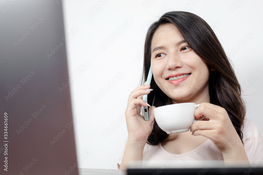A beautiful Asian woman talking on the phone while sipping coffee. A beautiful Asian woman talking on the phone while sipping coffee.