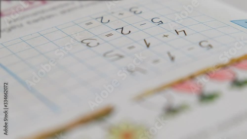 Preschool boy toddler, holding pencil, writing or doing math homework at the table. Hands close up
