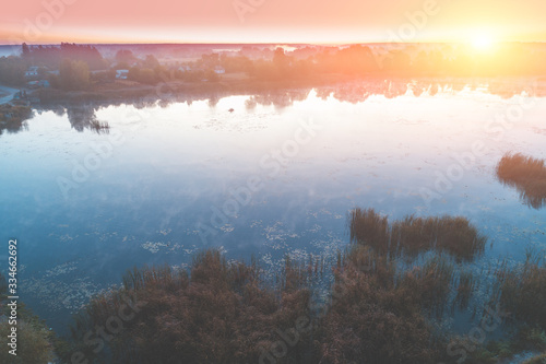 Early misty morning, sunrise over the lake. Rural landscape in summer. Aerial view