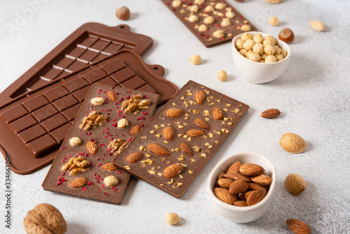 Milk chocolate bars with nuts on light background with molds. Homemade organic chocolate. Handmade tasty presents. Side view