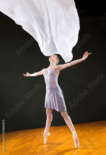 Fototapeta Naklejka Na Ścianę i Meble -  Young woman ballerina dancing with white fabric in the studio.