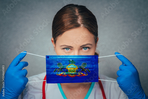 Coronavirus in U.S. State Pennsylvania, Female Doctor Portrait, protect Face surgical medical mask with Pennsylvania Flag. Illness, Virus Covid-19 in Pennsylvania photo