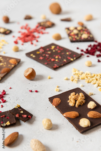 Homemade milk and dark chocolate bars with dried berries and nuts on light background. Side view. Chocolatier work