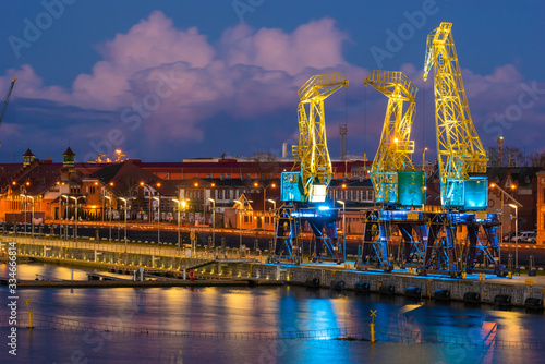 Illuminated old port cranes on a boulevard in Szczecin against the backdrop of storm clouds