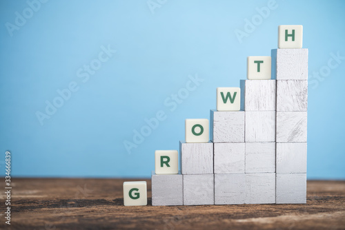 Business and finance growth concept. Green word GROWTH on wooden block as graph rising. Success performance or achieve KPI target plan and strategy.