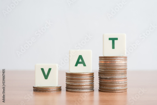 Konstfotografi Word VAT on step stacked coins as graph up over white background