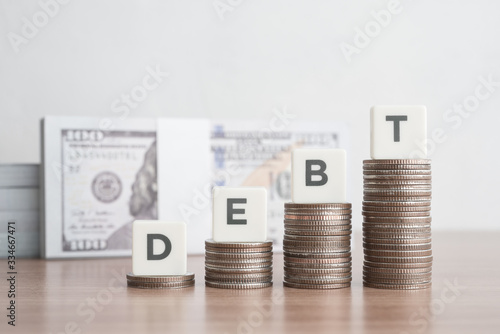 Fotobehang Word DEBT on step stacked coins as graph up with banknotes background