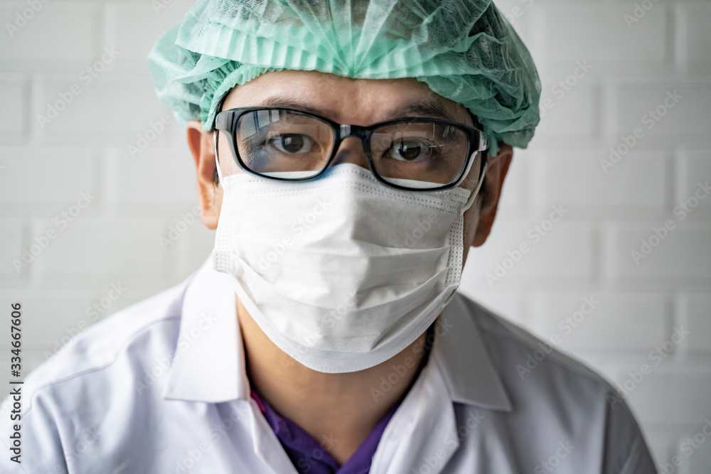 Asian male doctor wearing protective surgical mask lab coat and hair net, in research laboratory in china Wuhan, testing coronavirus COVID-19 disease portrait head shot looking with protection gear